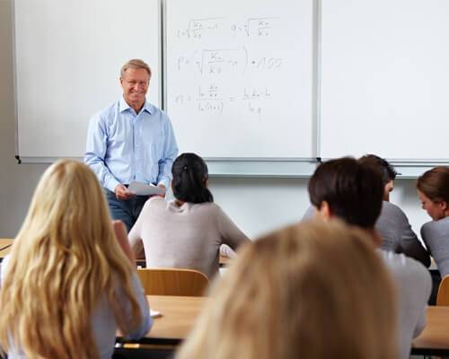 Male teacher lecturing students in classroom.