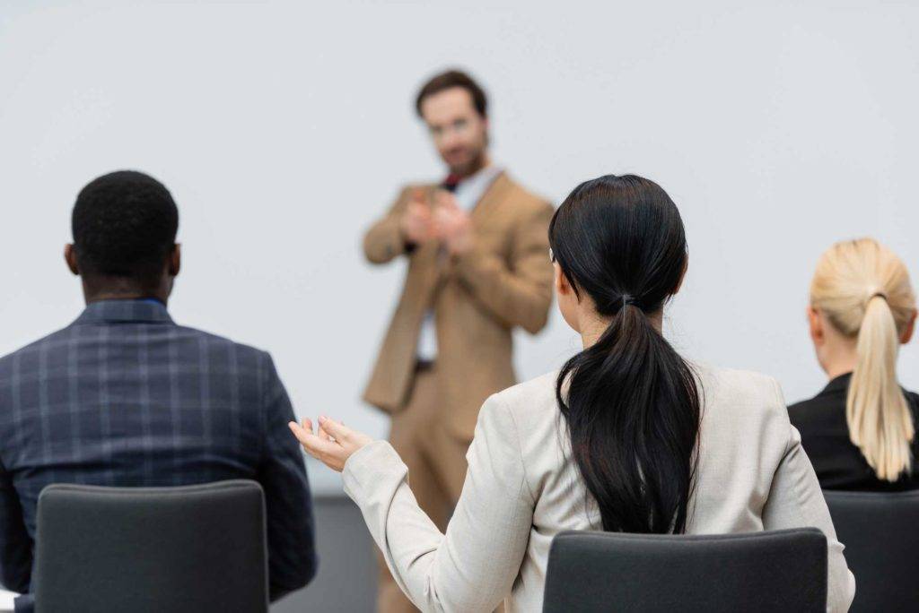 Woman raises hand in business meeting.