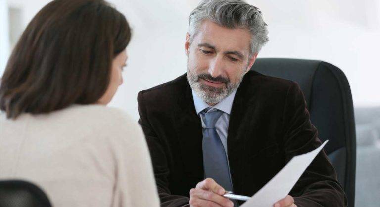 Man in suit explaining document to woman, workers' compensation certification, workers' compensation certification